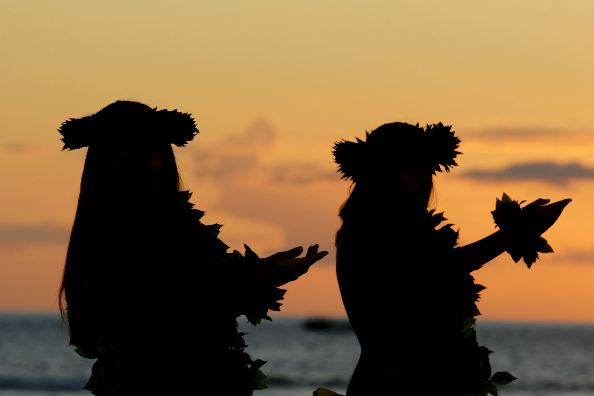 a couple of women standing on a beach at sunset
