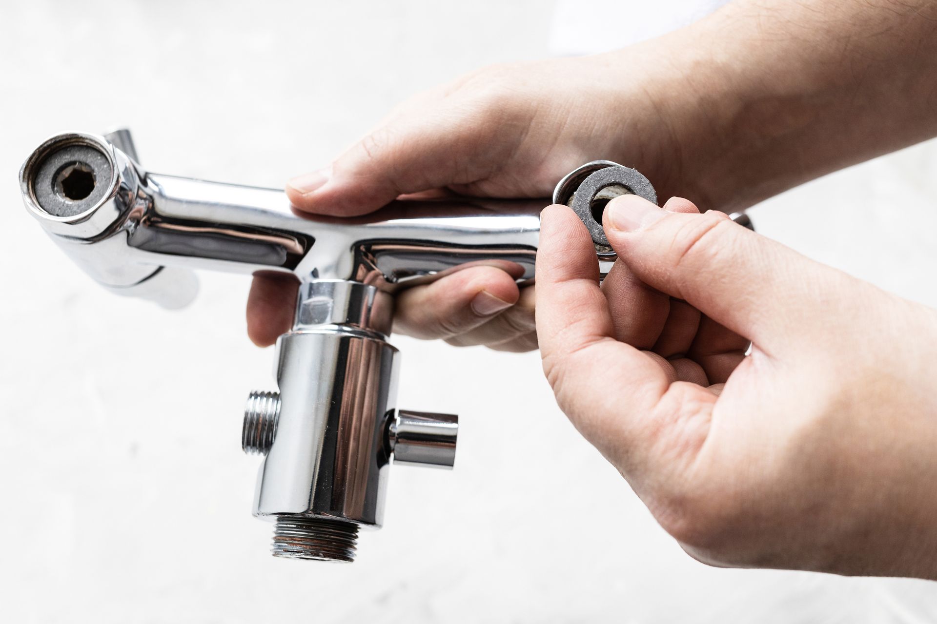 A person is holding a shower head in their hands.