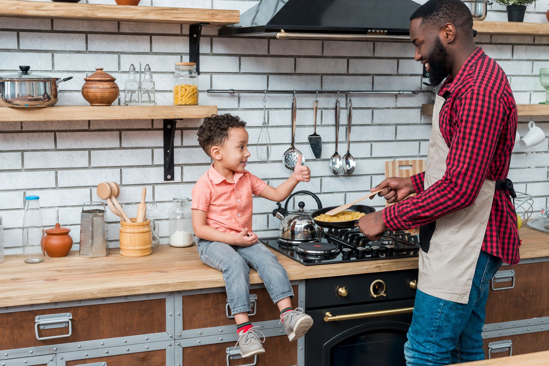 A man and a little boy are cooking in a kitchen.