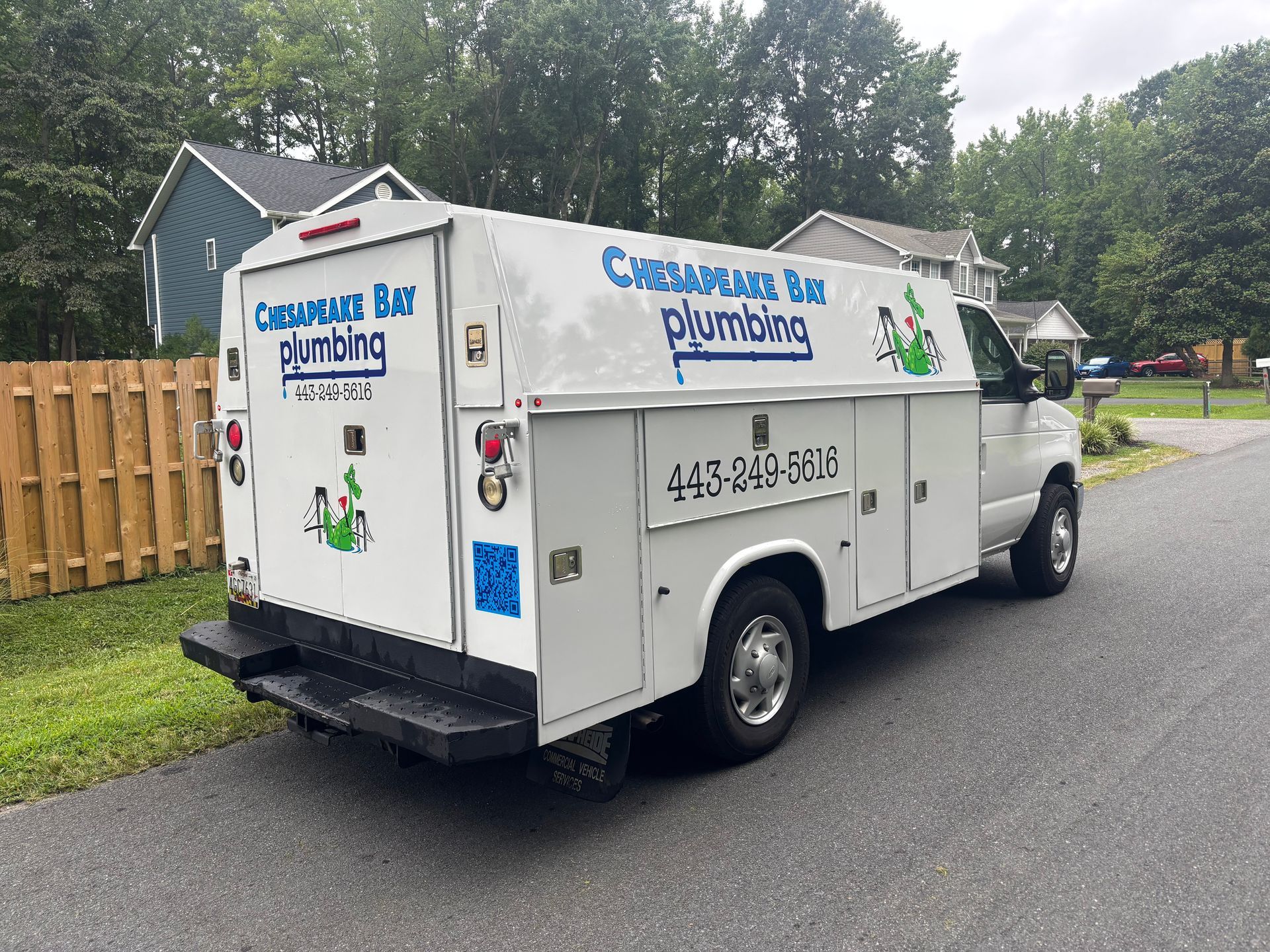 White Chesapeake Bay Plumbing truck parked on a street in front of a house.