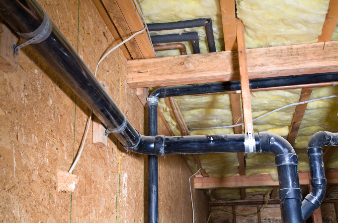 A man is working on a pipe in a wooden frame.