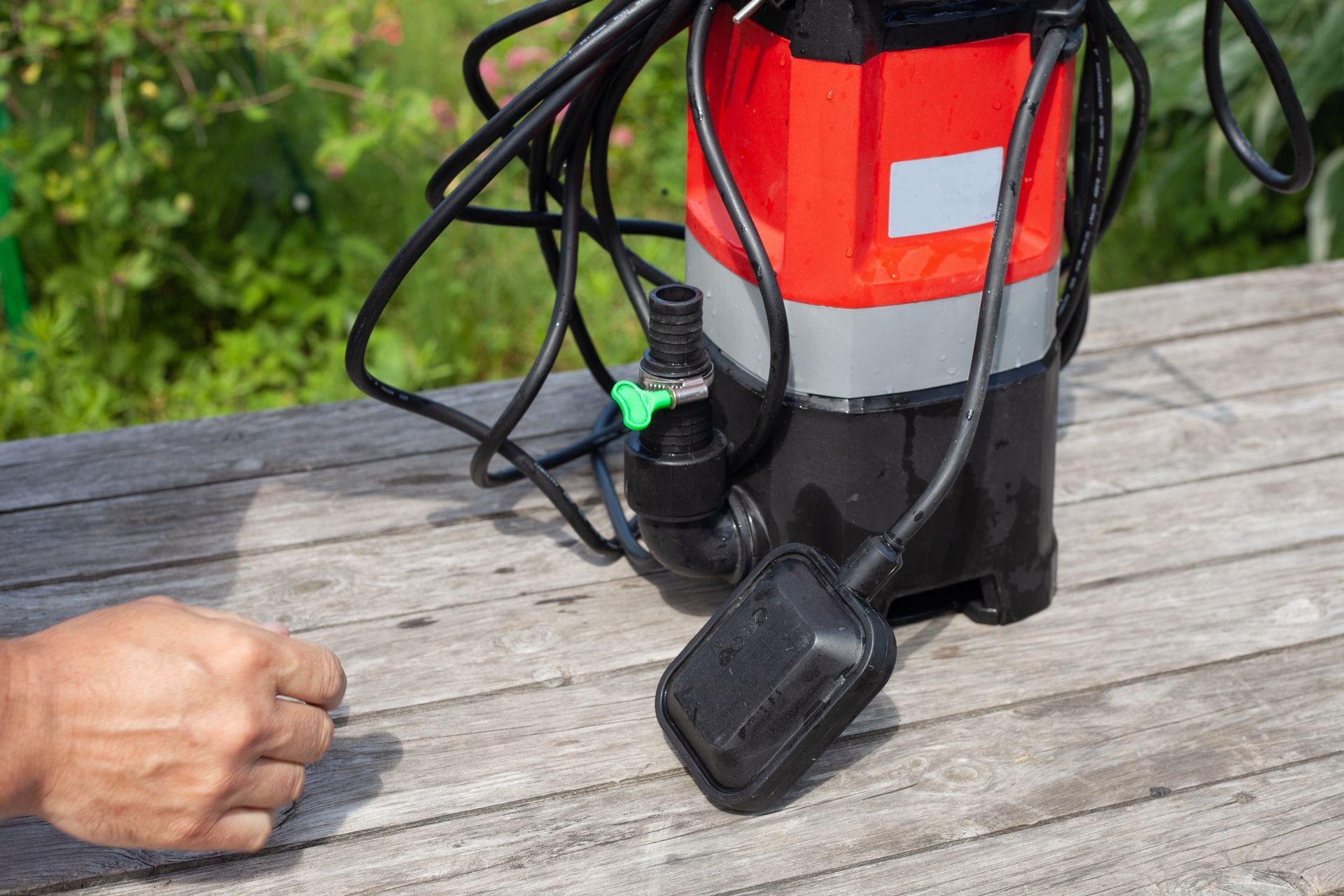 A person is holding a water pump on a wooden table.