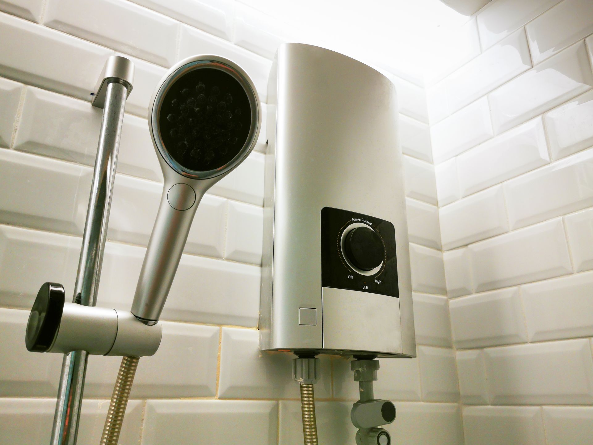A shower head is attached to a water heater in a bathroom.