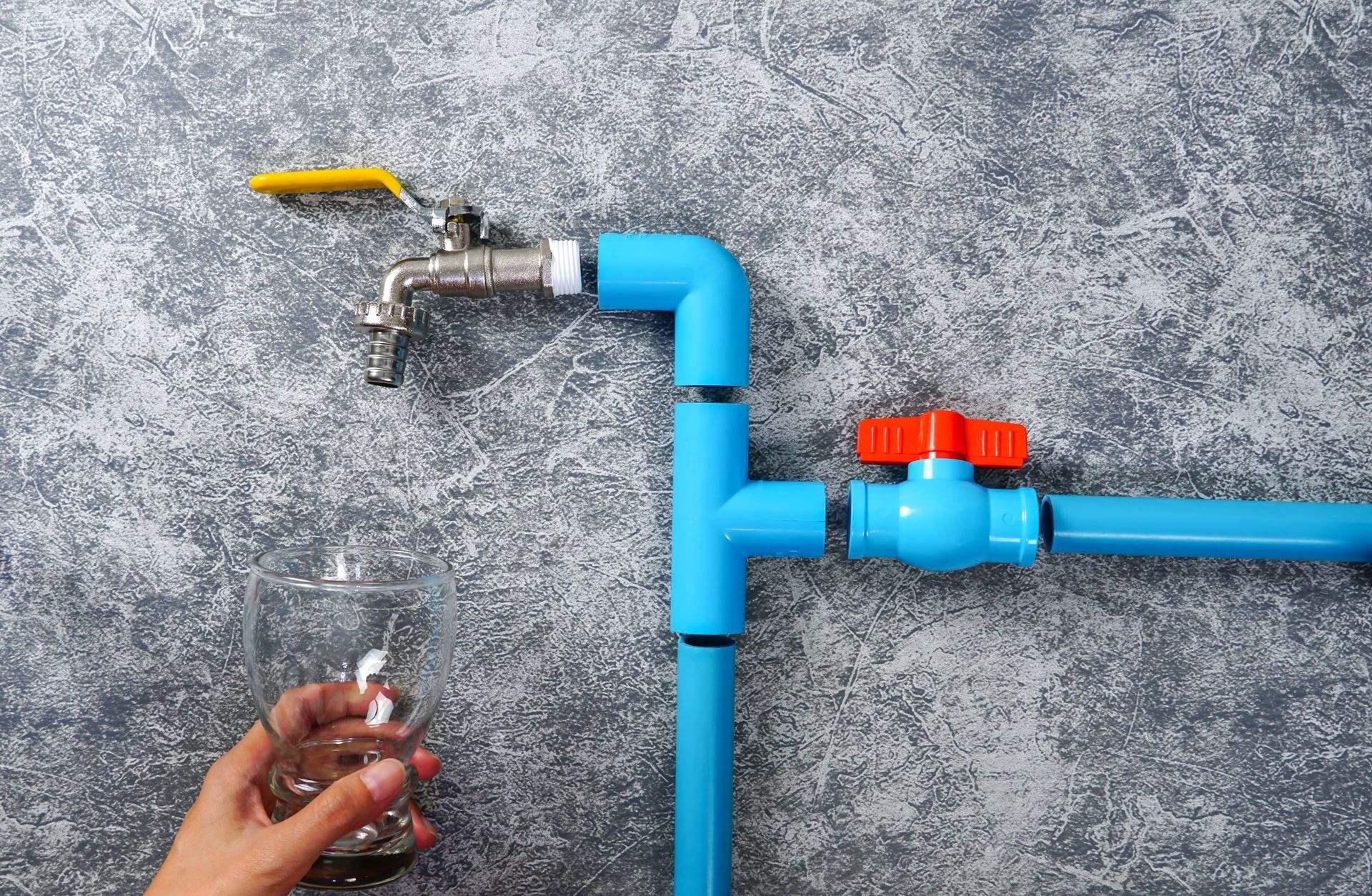A person is pouring water from a faucet into a glass.