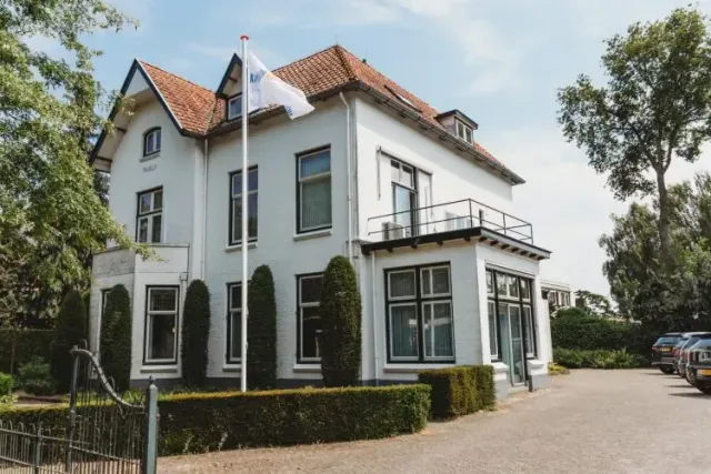 Een groot wit huis met een vlag ervoor