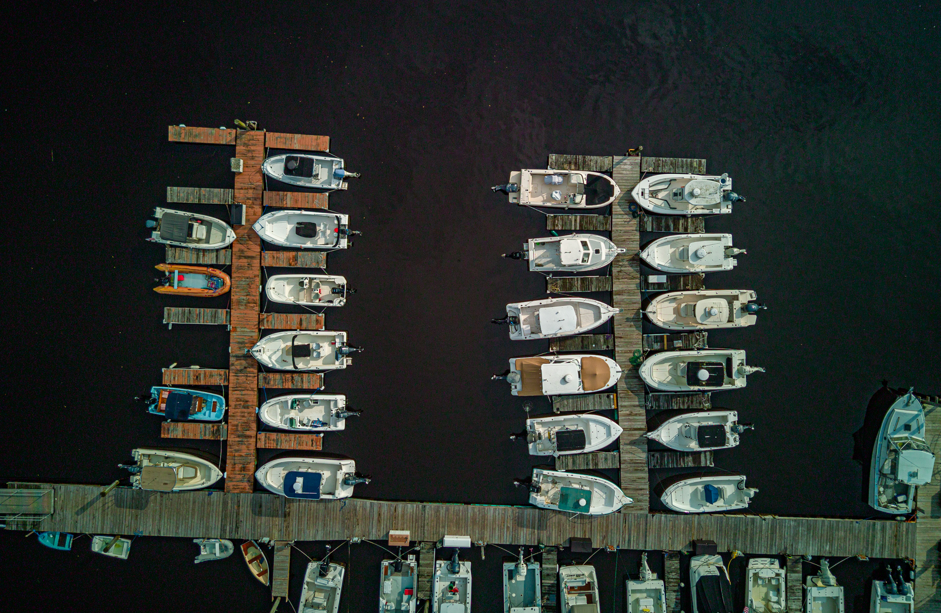 A bunch of boats are docked at a dock at night