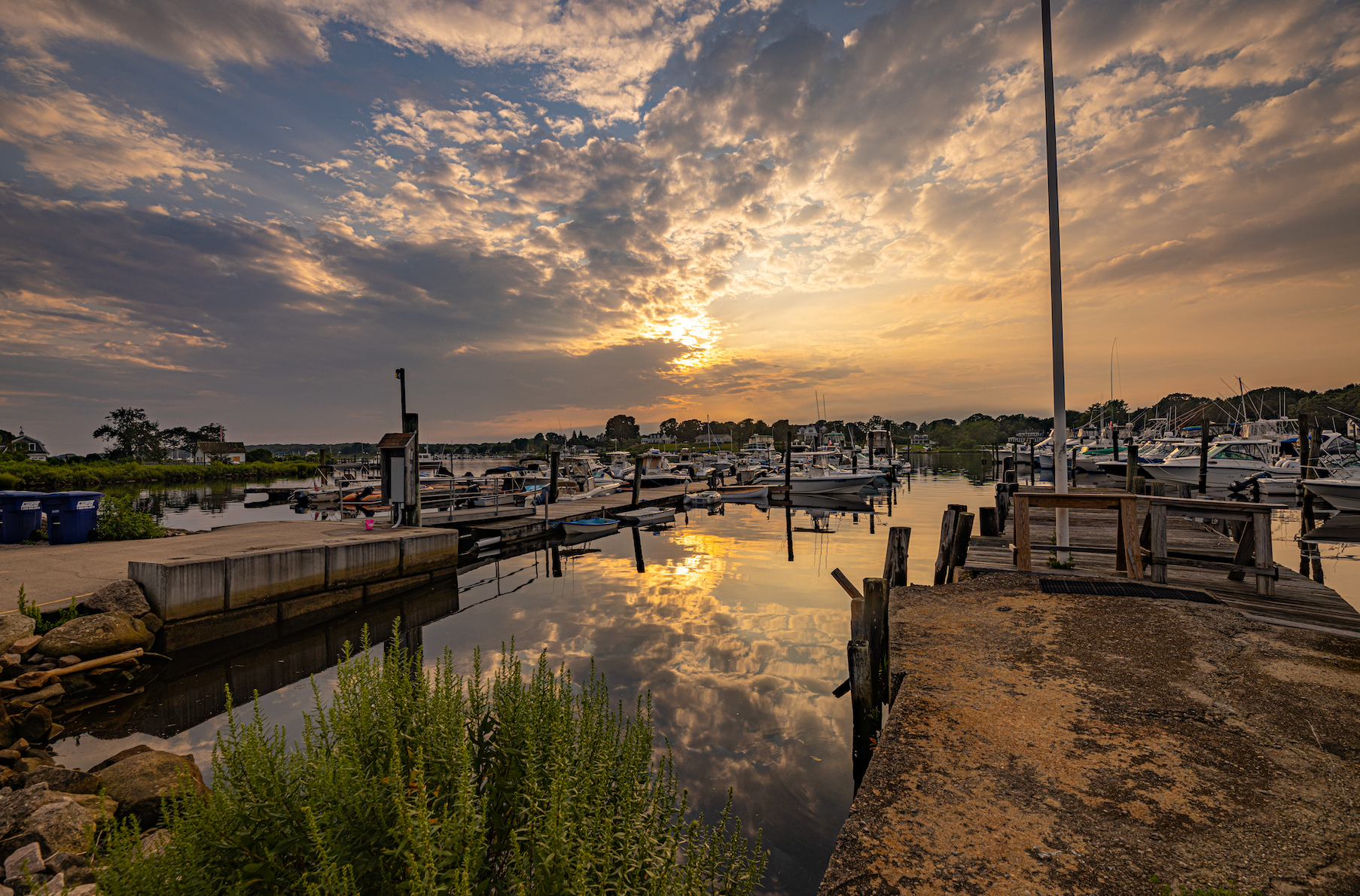 A sunset over a marina with boats docked and a dock in the foreground.