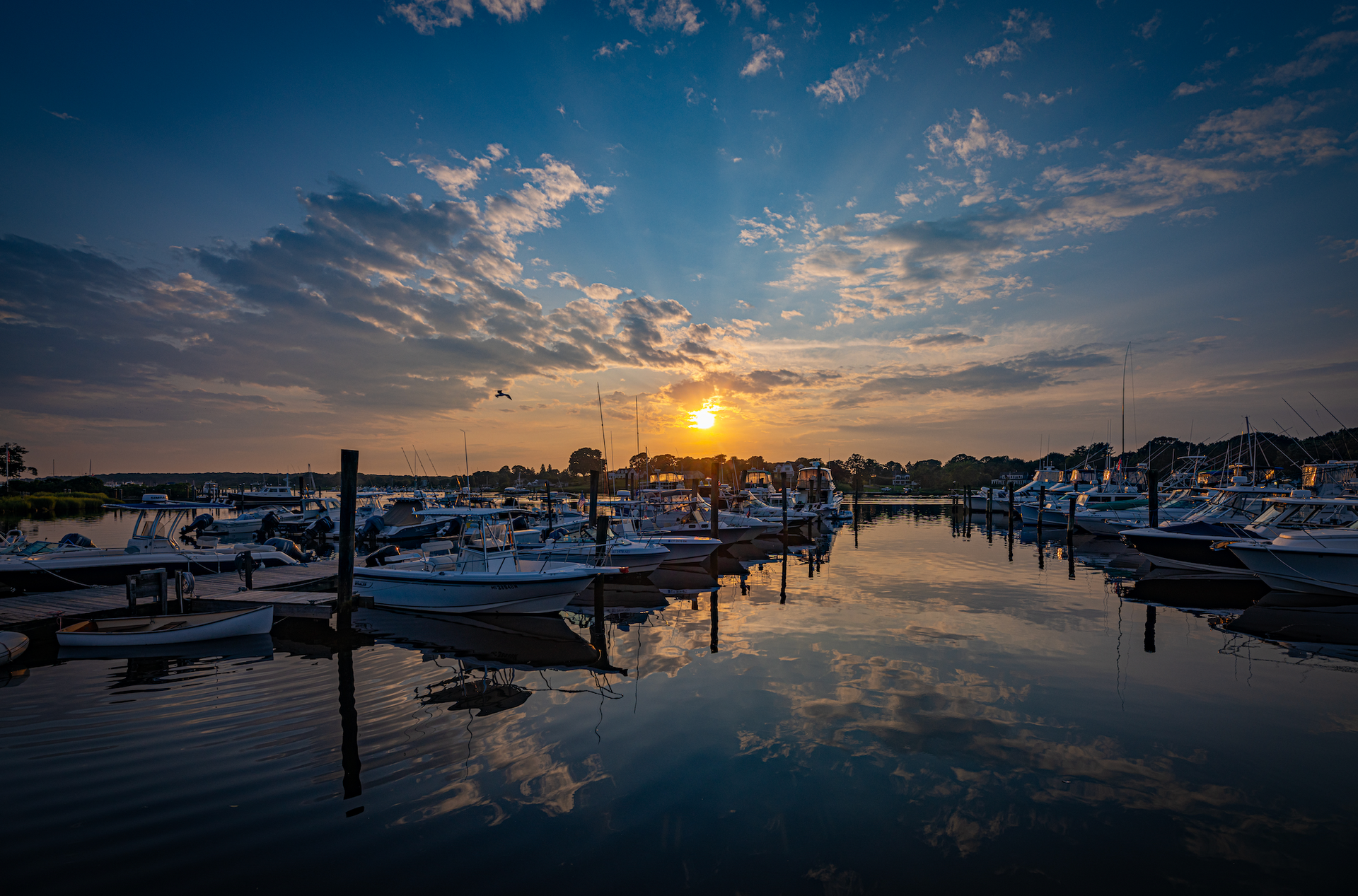 The sun is setting over a marina filled with boats.