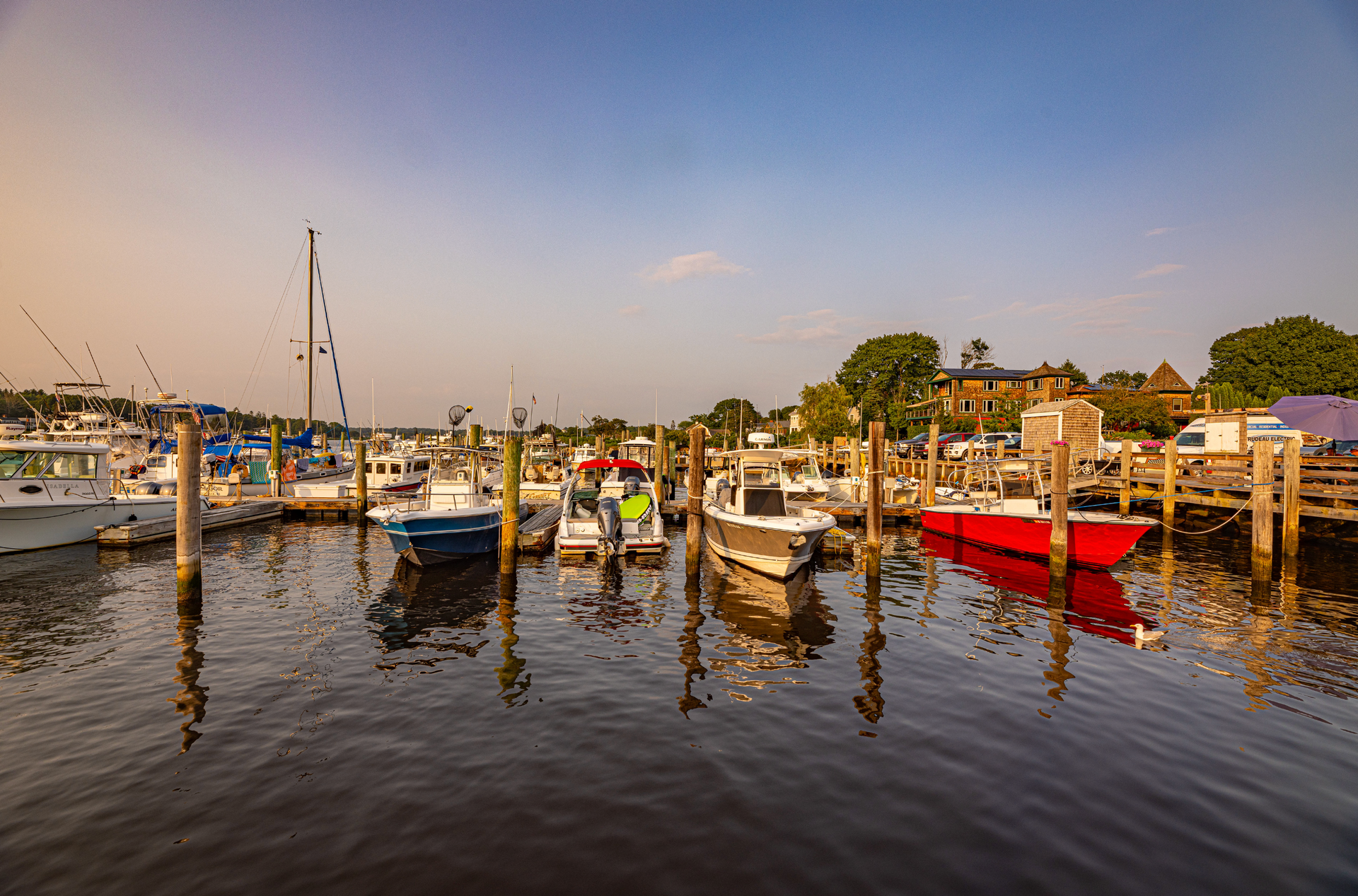 A row of boats are docked at a marina.