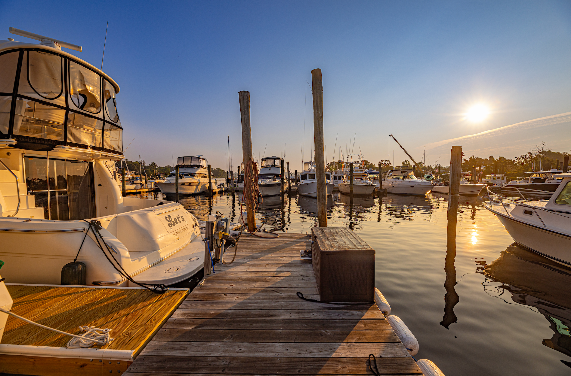A group of boats are docked at a marina at sunset.