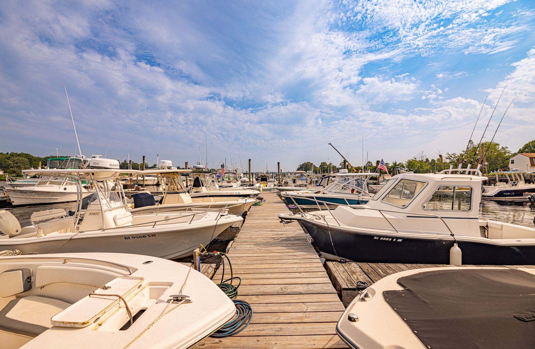 A row of boats are docked at a marina on a sunny day.