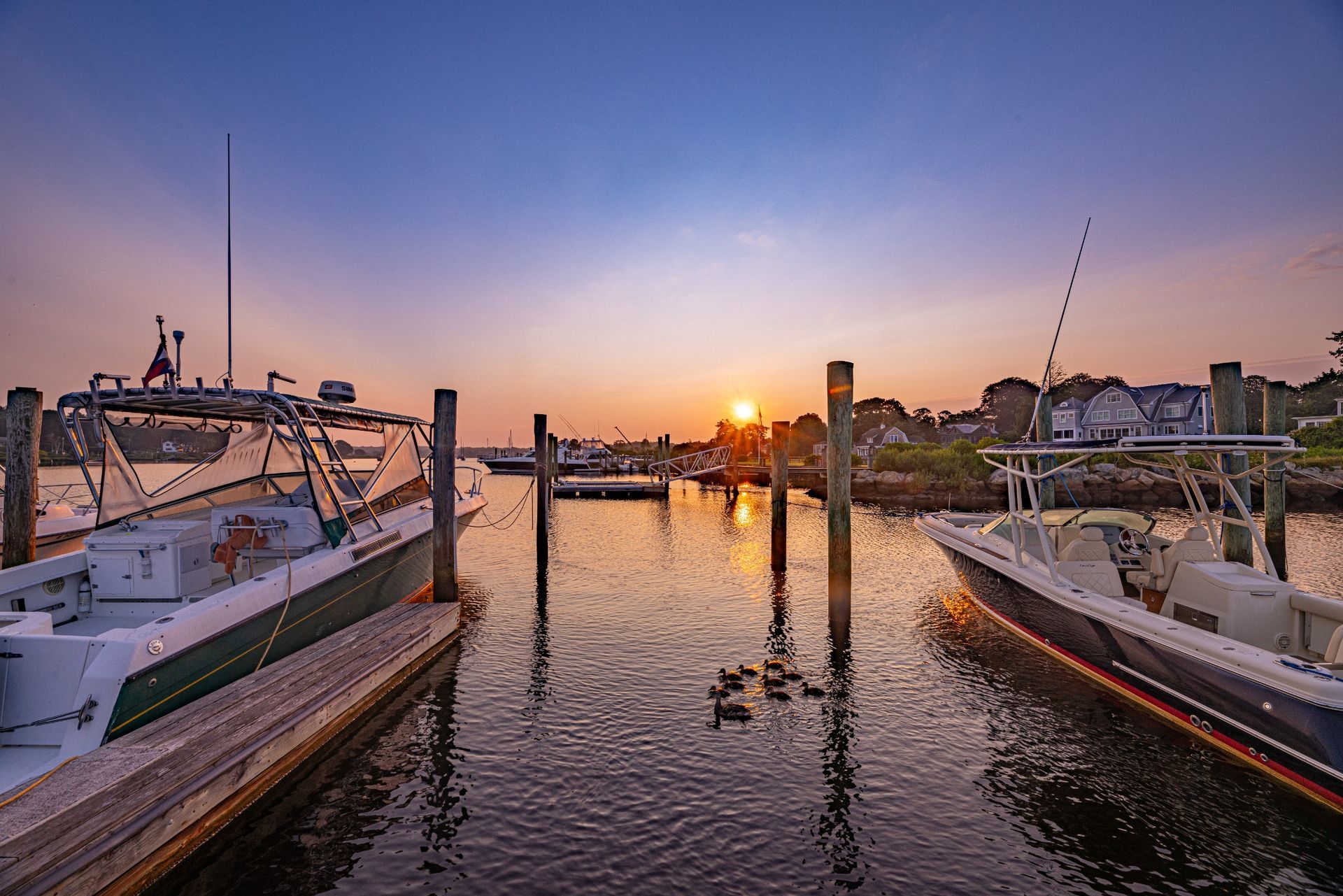 A group of boats are docked in a harbor at sunset.