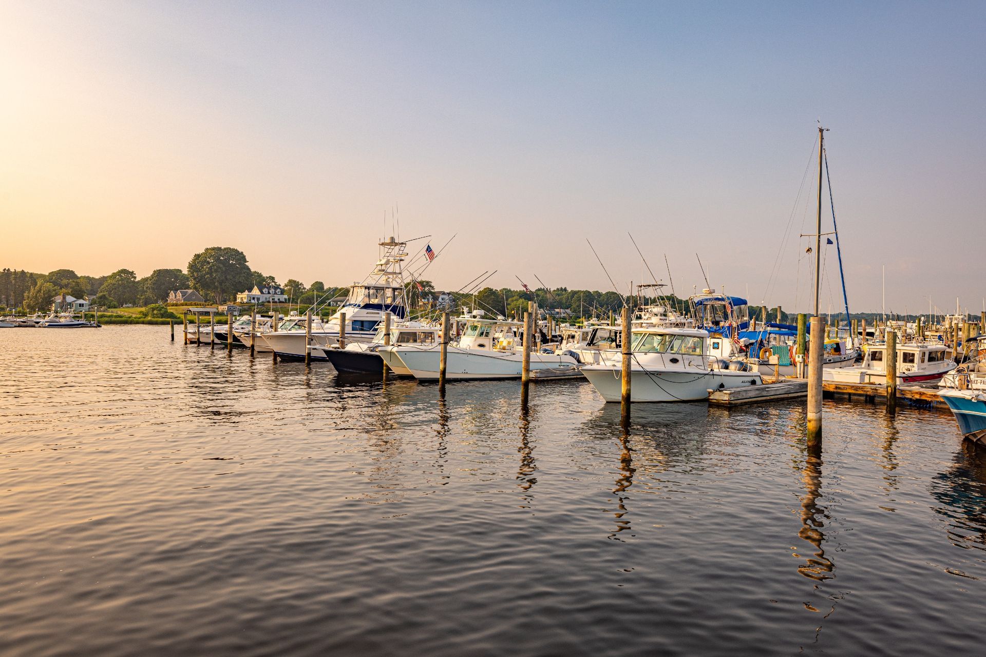 A row of boats are docked at a marina.