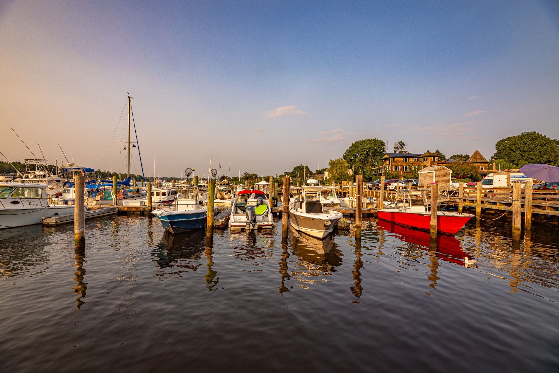 A row of boats are docked at a marina.