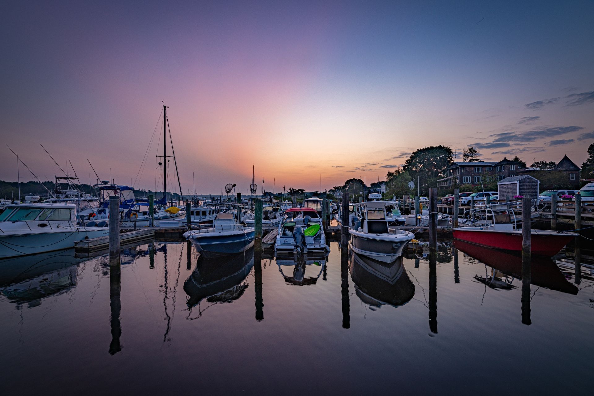 A group of boats are docked in a marina at sunset.