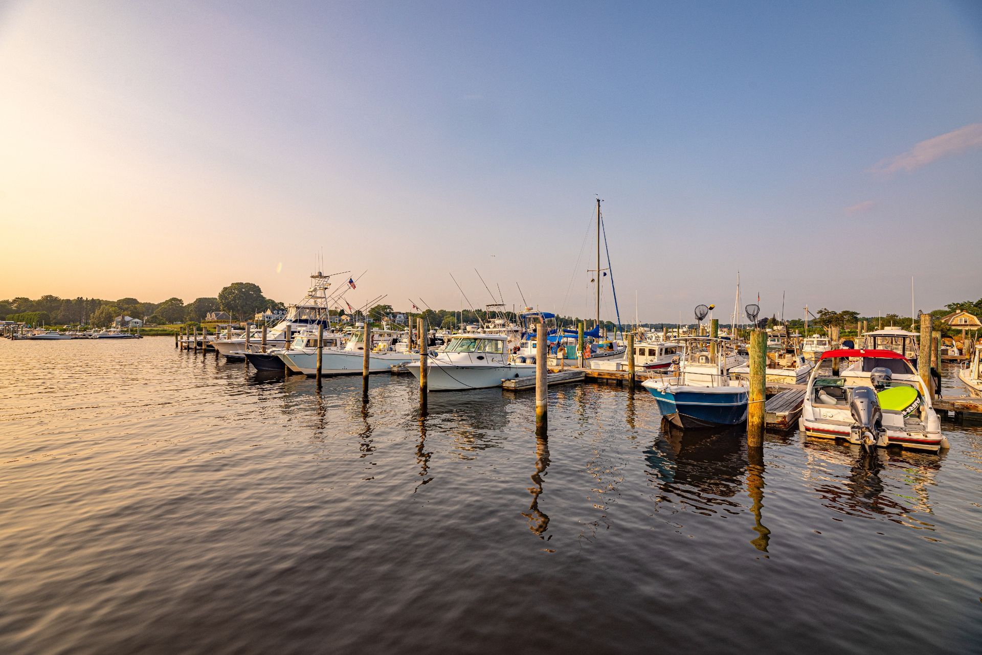 A row of boats are docked at a marina.