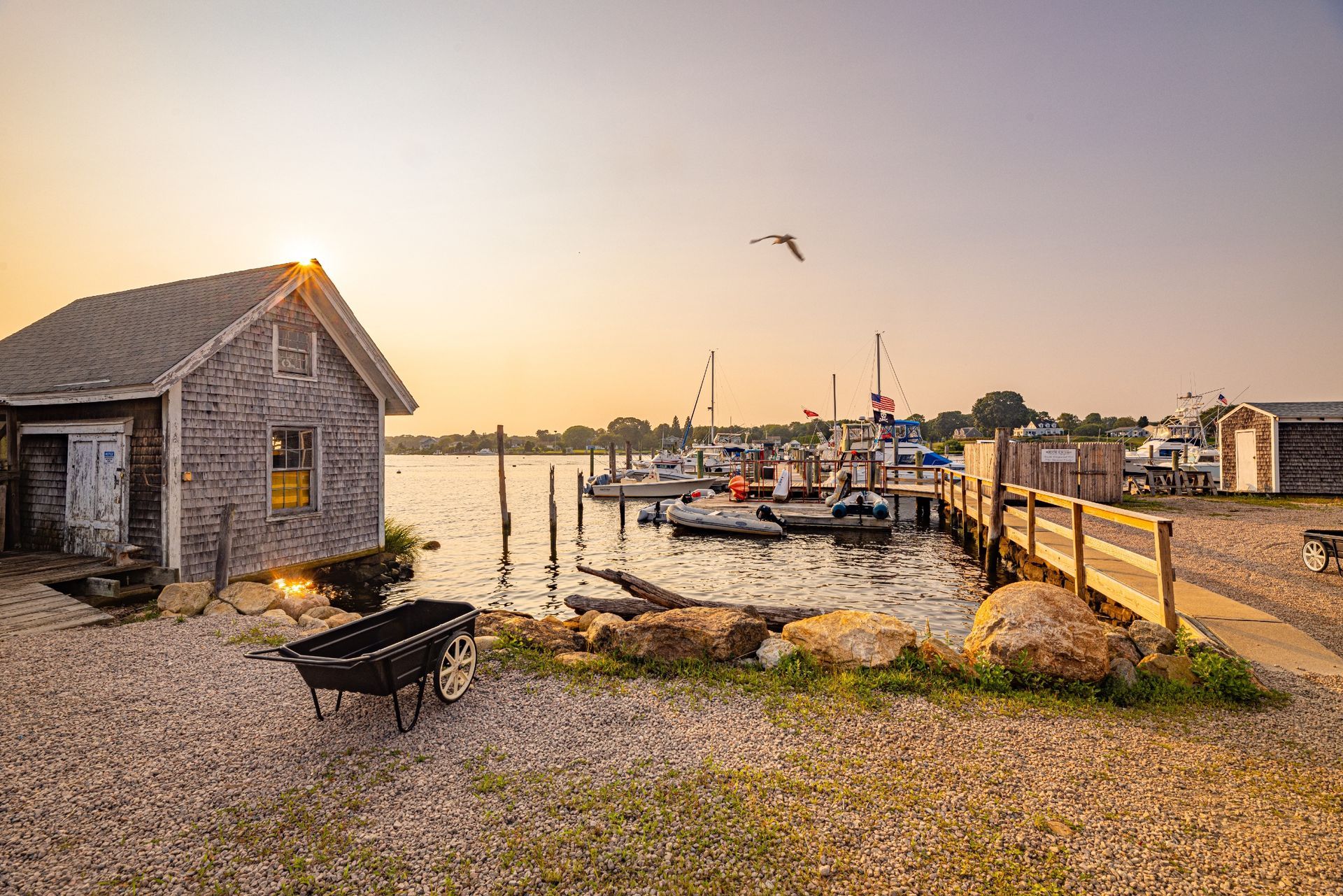 A dock with boats docked at sunset with a wheelbarrow in the foreground.
