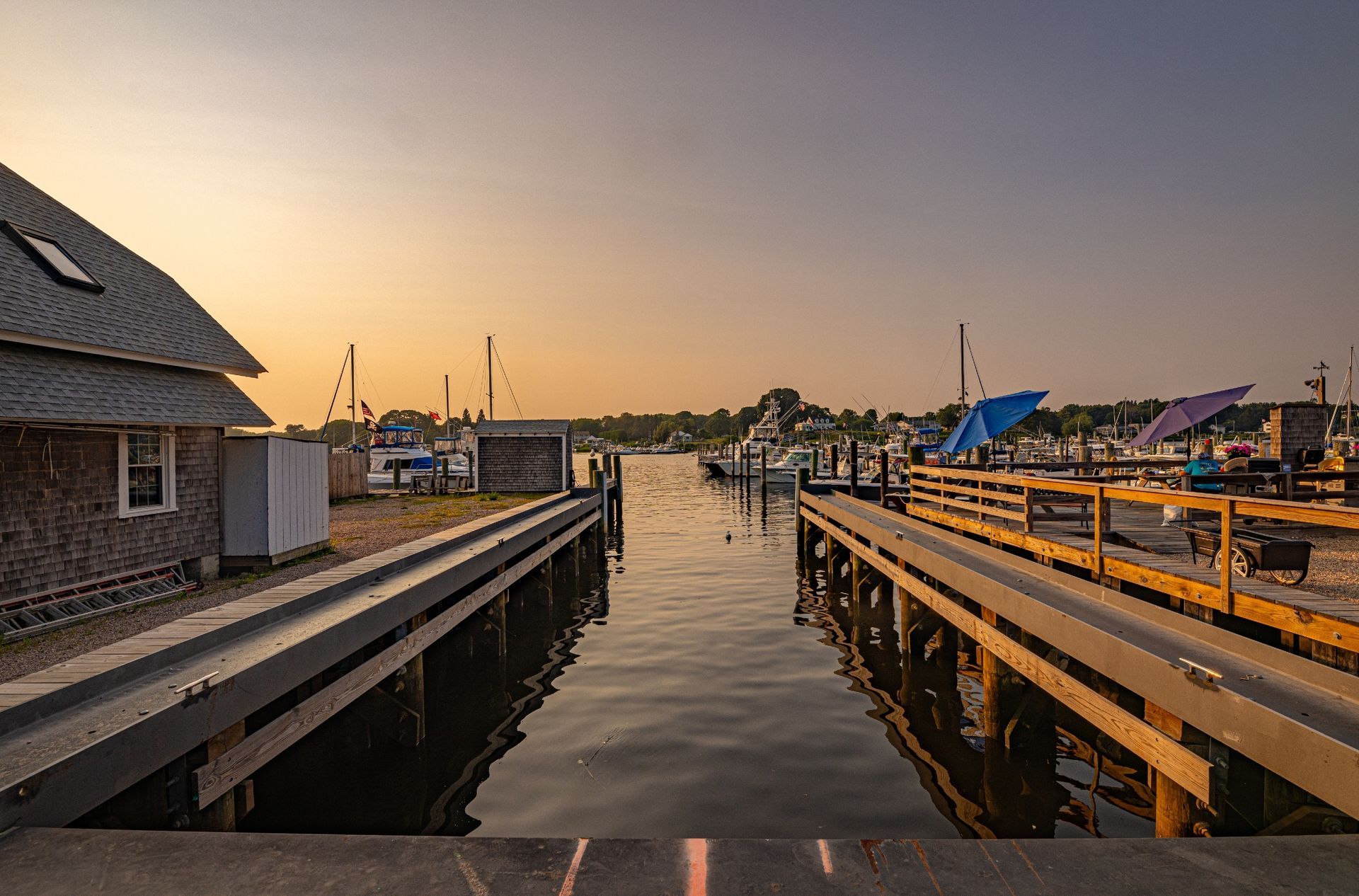 A wooden dock leading into a body of water with boats docked in the background.
