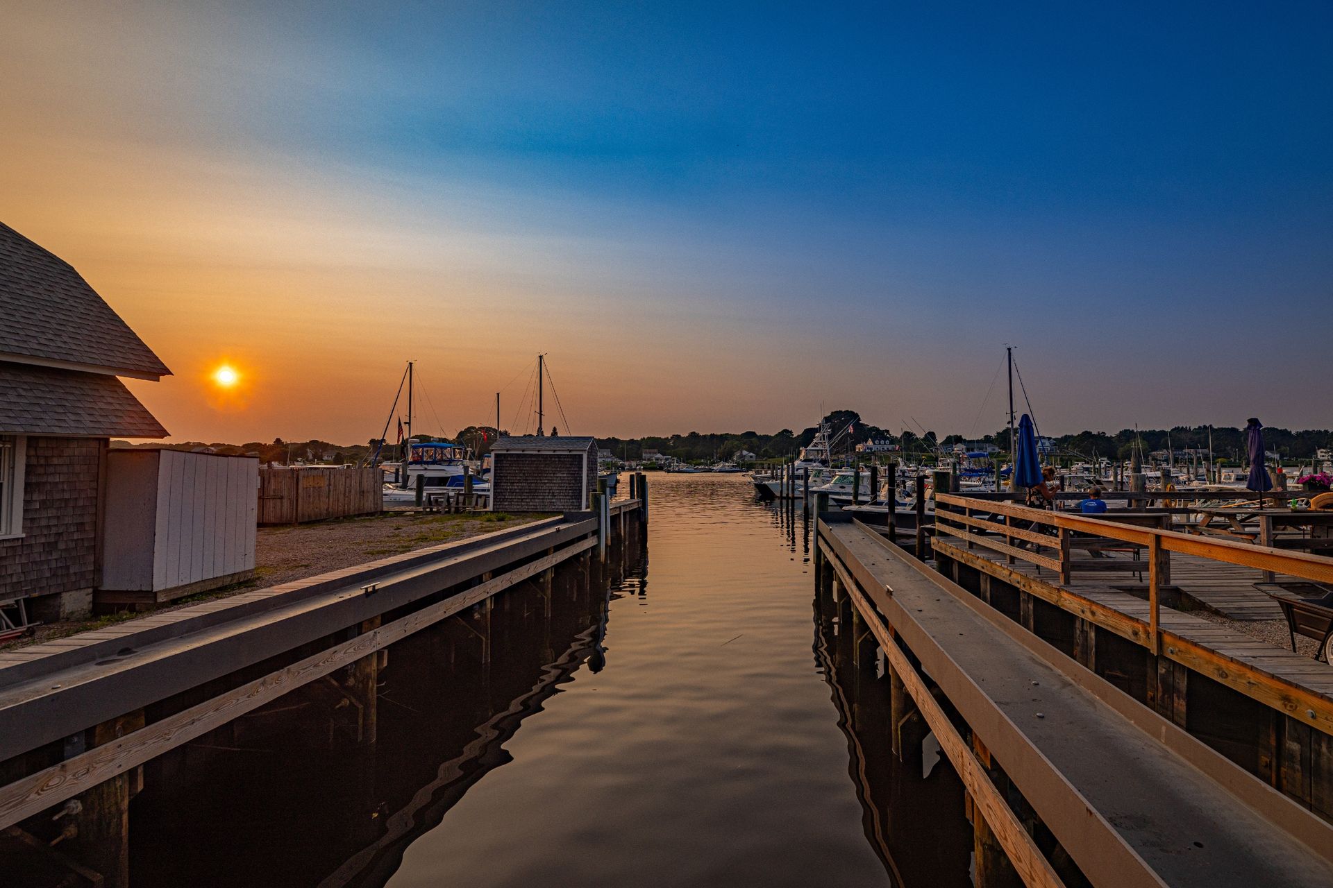 A dock with boats docked at a marina at sunset.