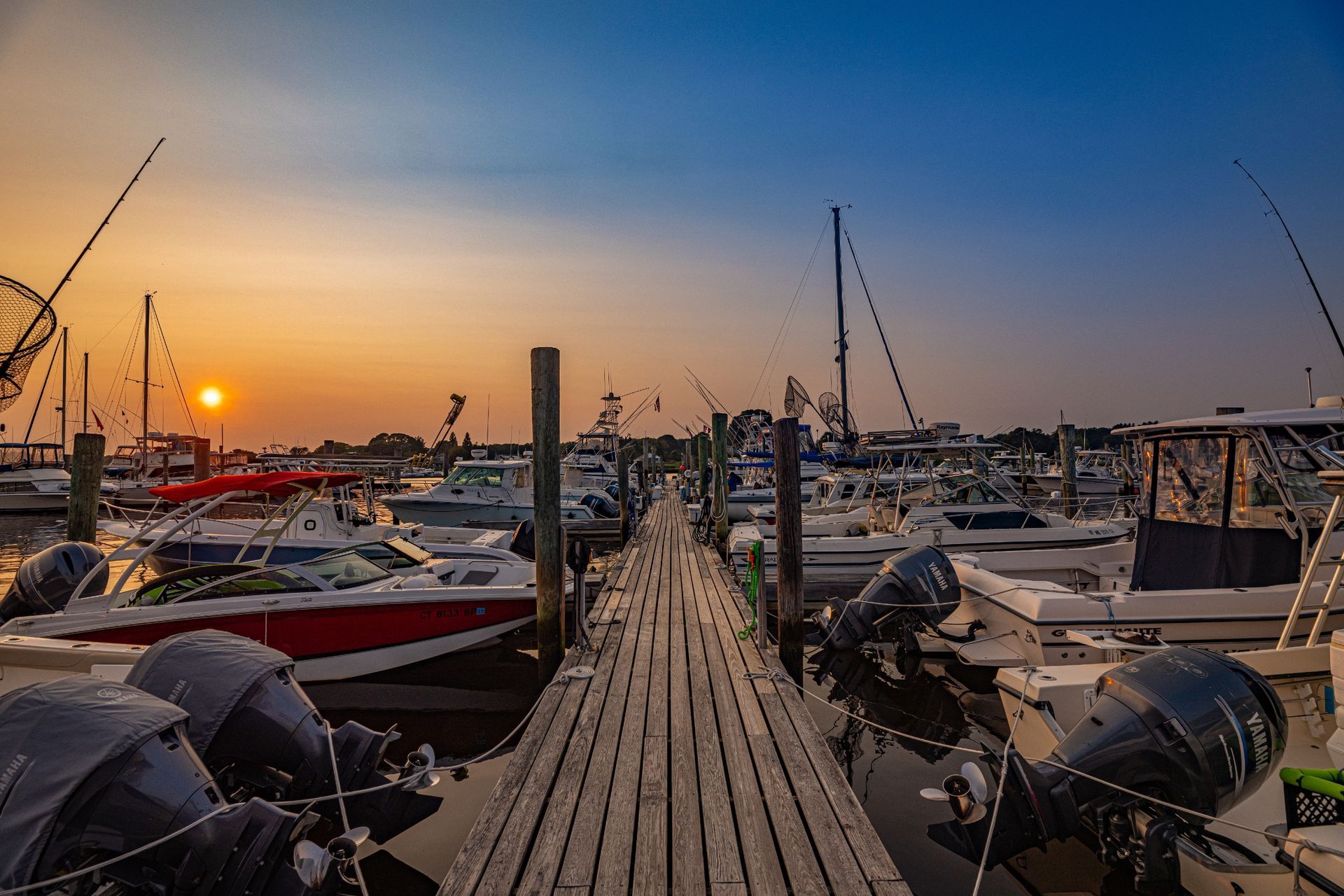A dock filled with boats at a marina at sunset.