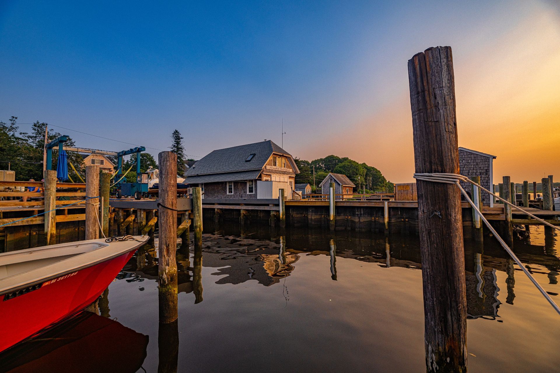 A red boat is docked at a dock at sunset.