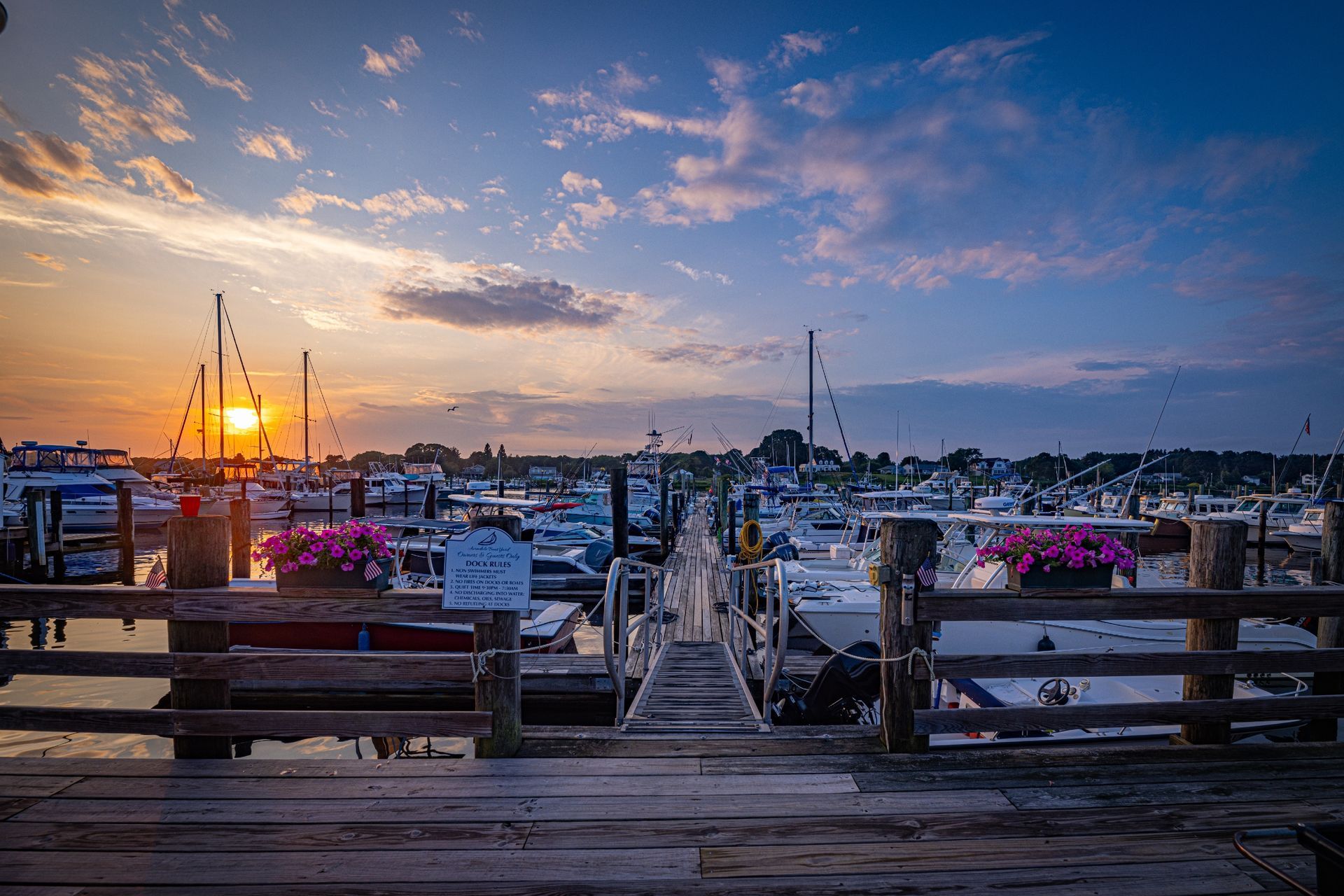 A dock with boats docked at a marina at sunset.