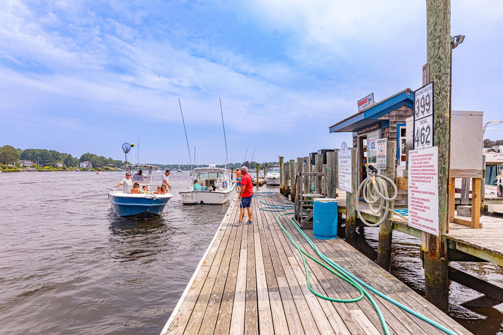 A man is standing on a dock next to boats in the water.