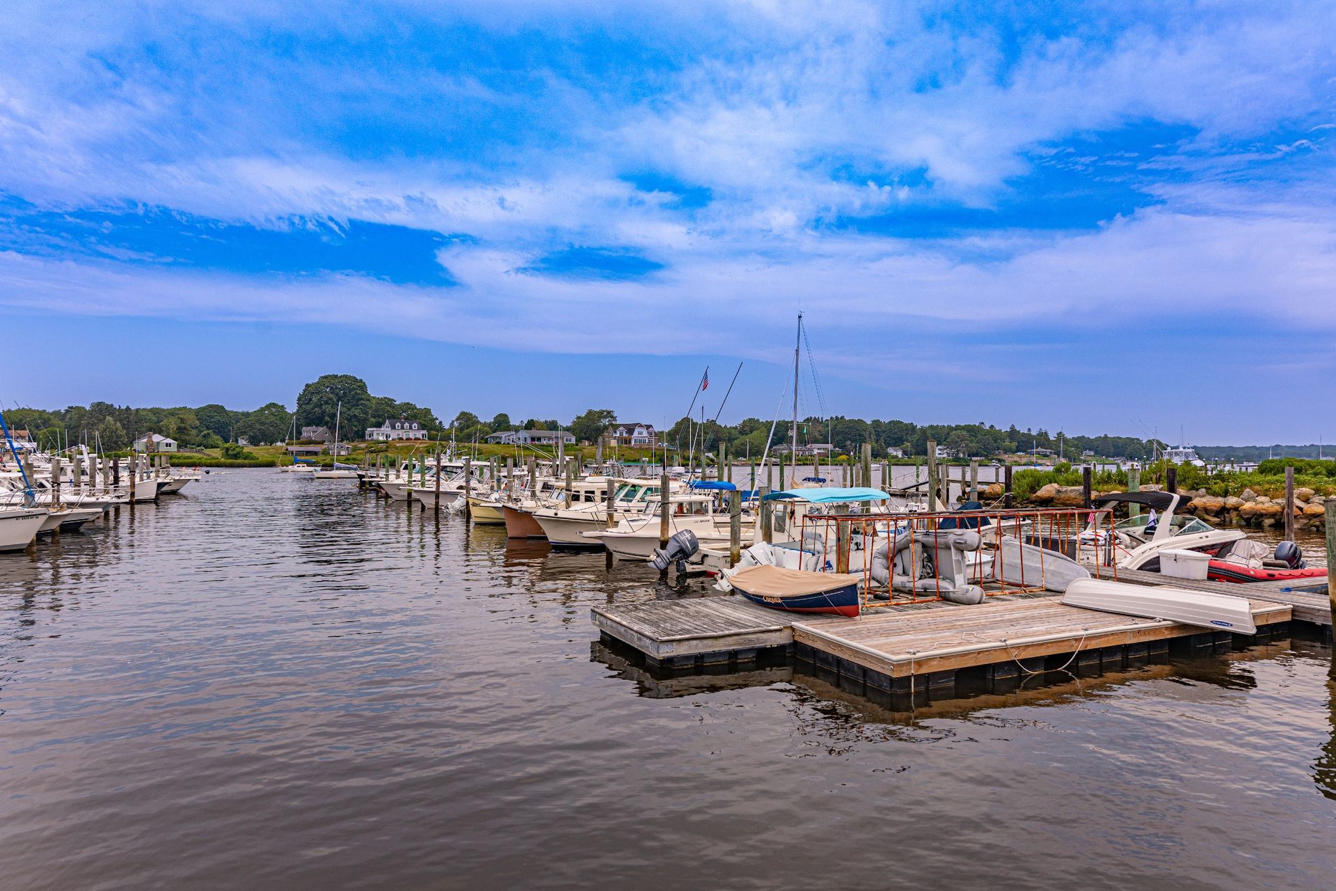 A row of boats are docked at a marina on a sunny day.