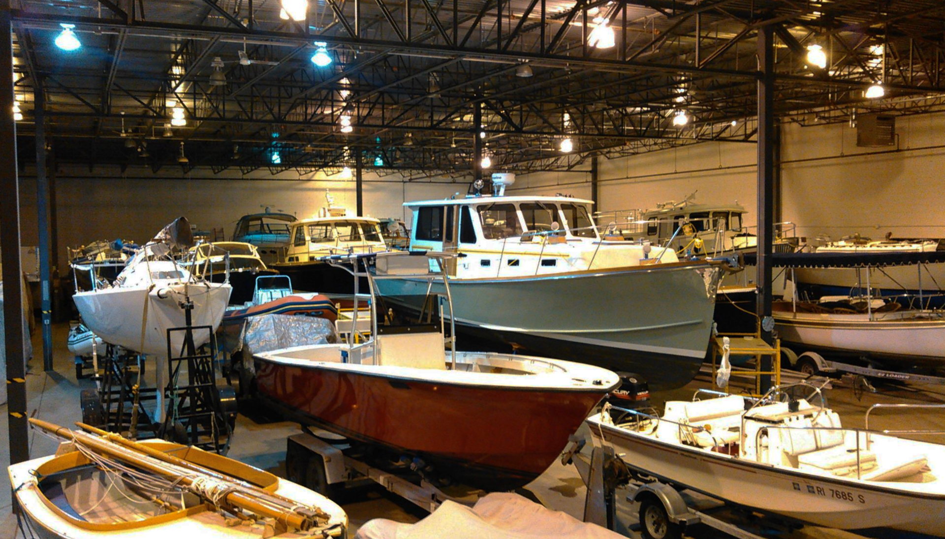 A warehouse filled with lots of boats including a red boat