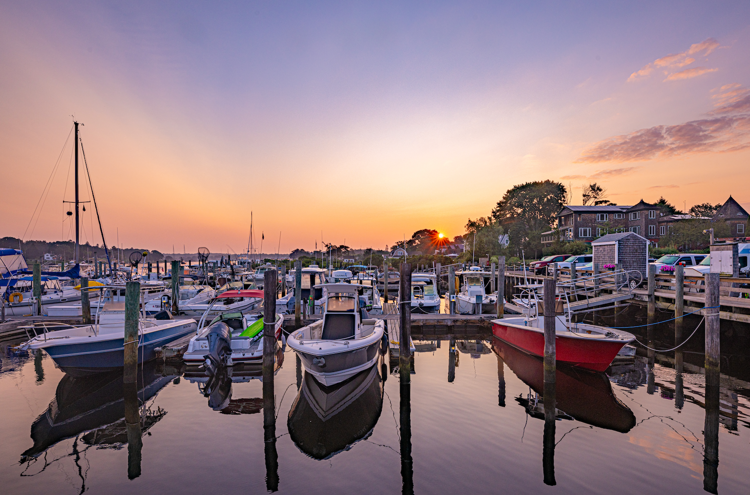 A bunch of boats are docked in a harbor at sunset.