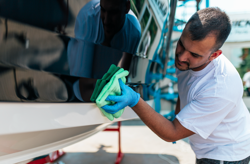 A man is cleaning a boat with a cloth.