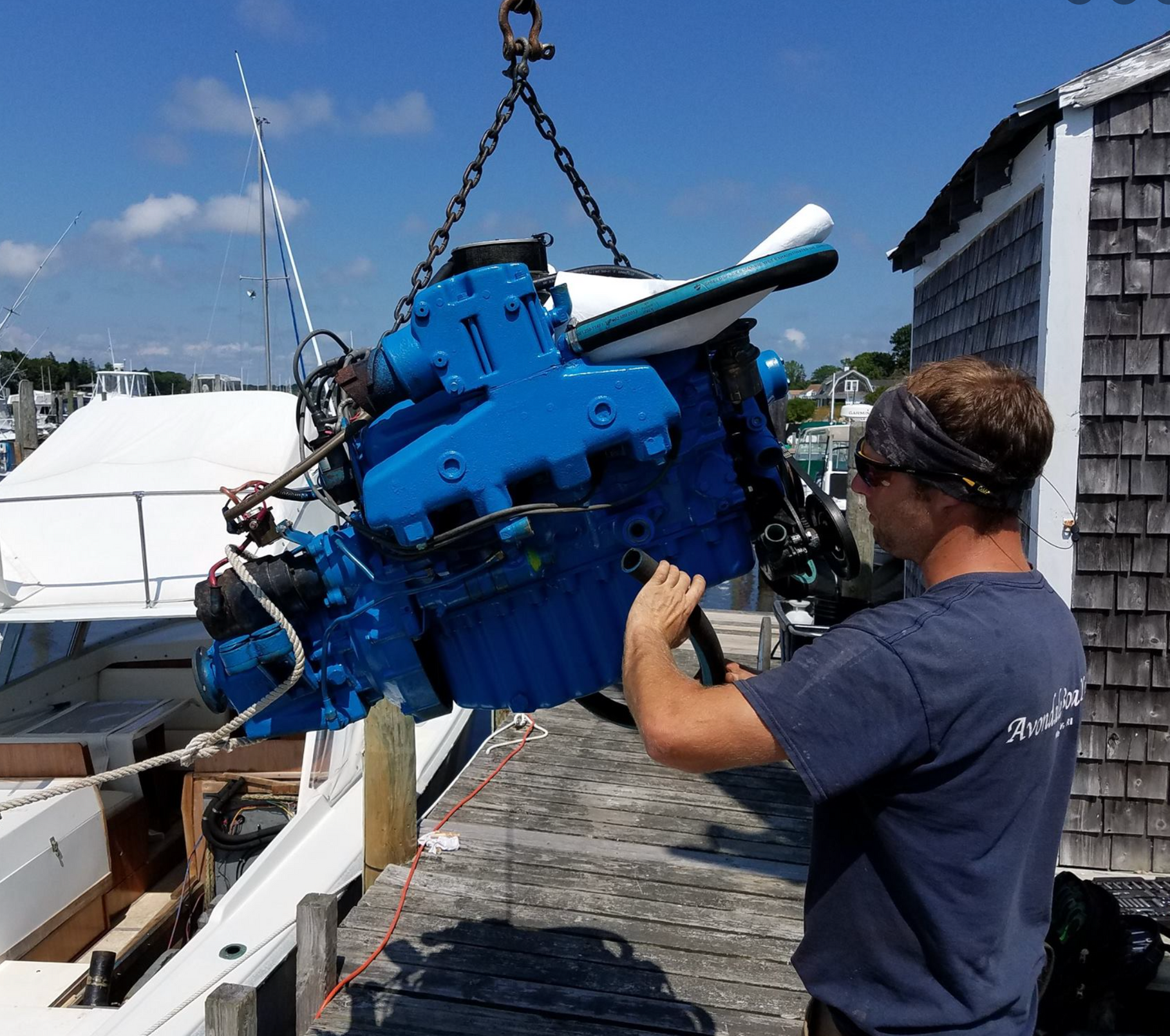 A man in a blue shirt is lifting a large blue engine