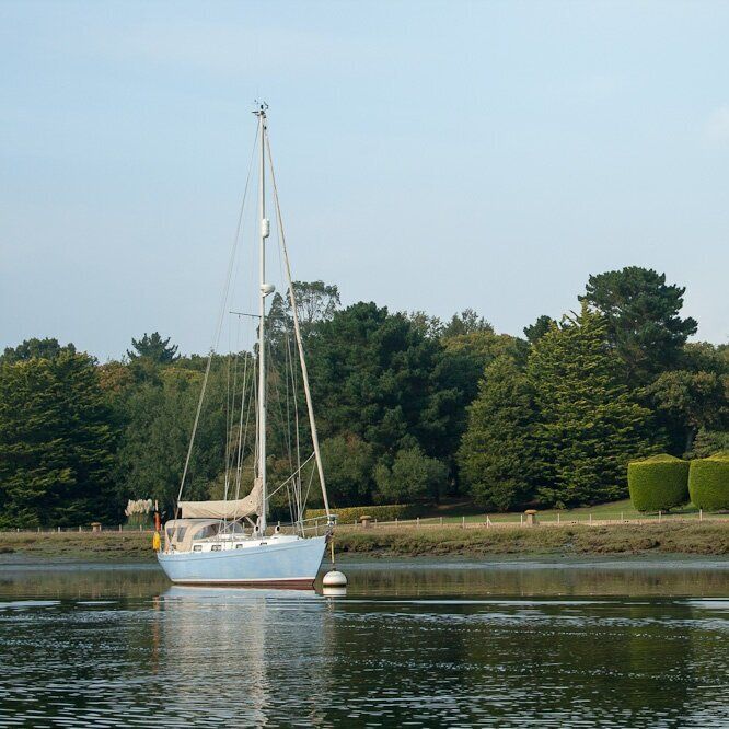 A boat is floating on a body of water with trees in the background
