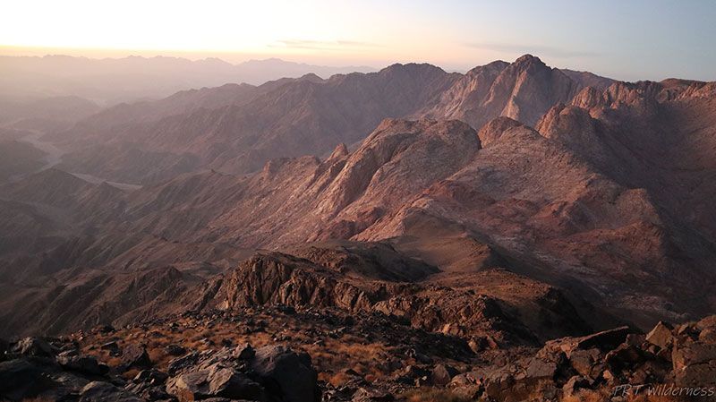 A mountain range with a sunset in the background