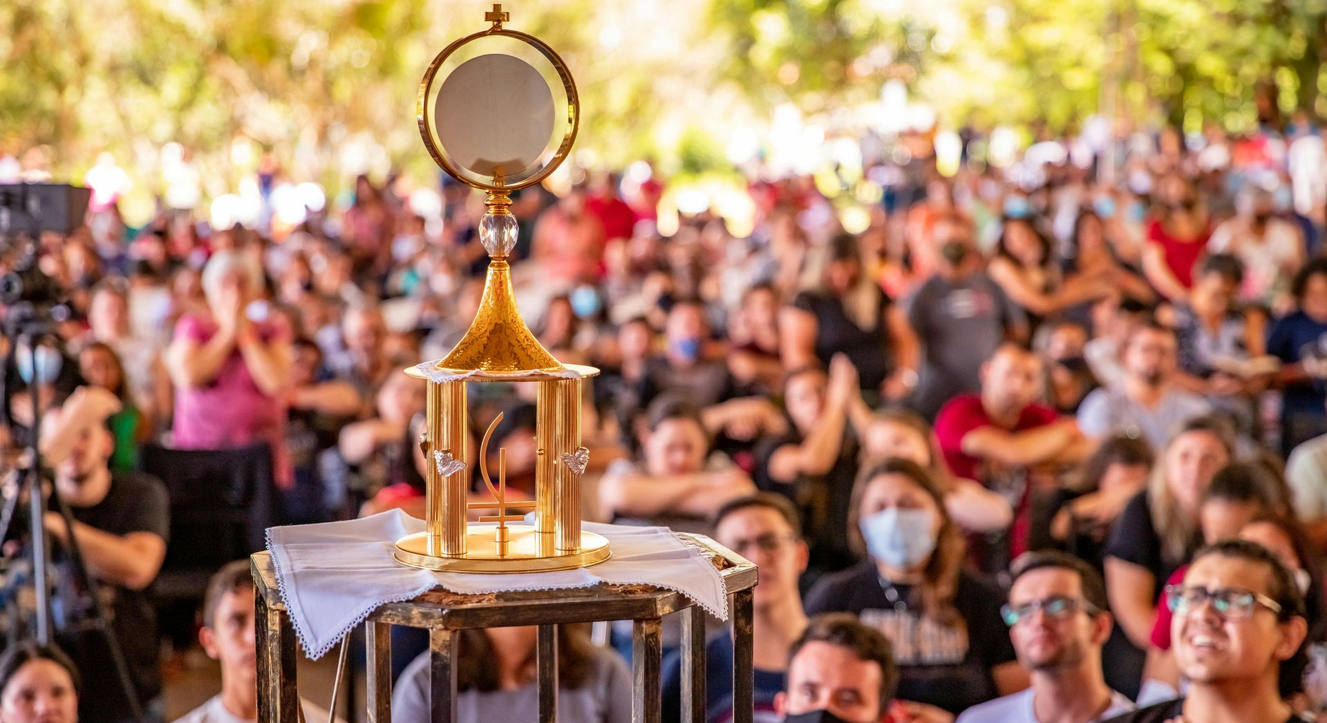 A monstrance with a consecrated host is displayed before a crowd of people.