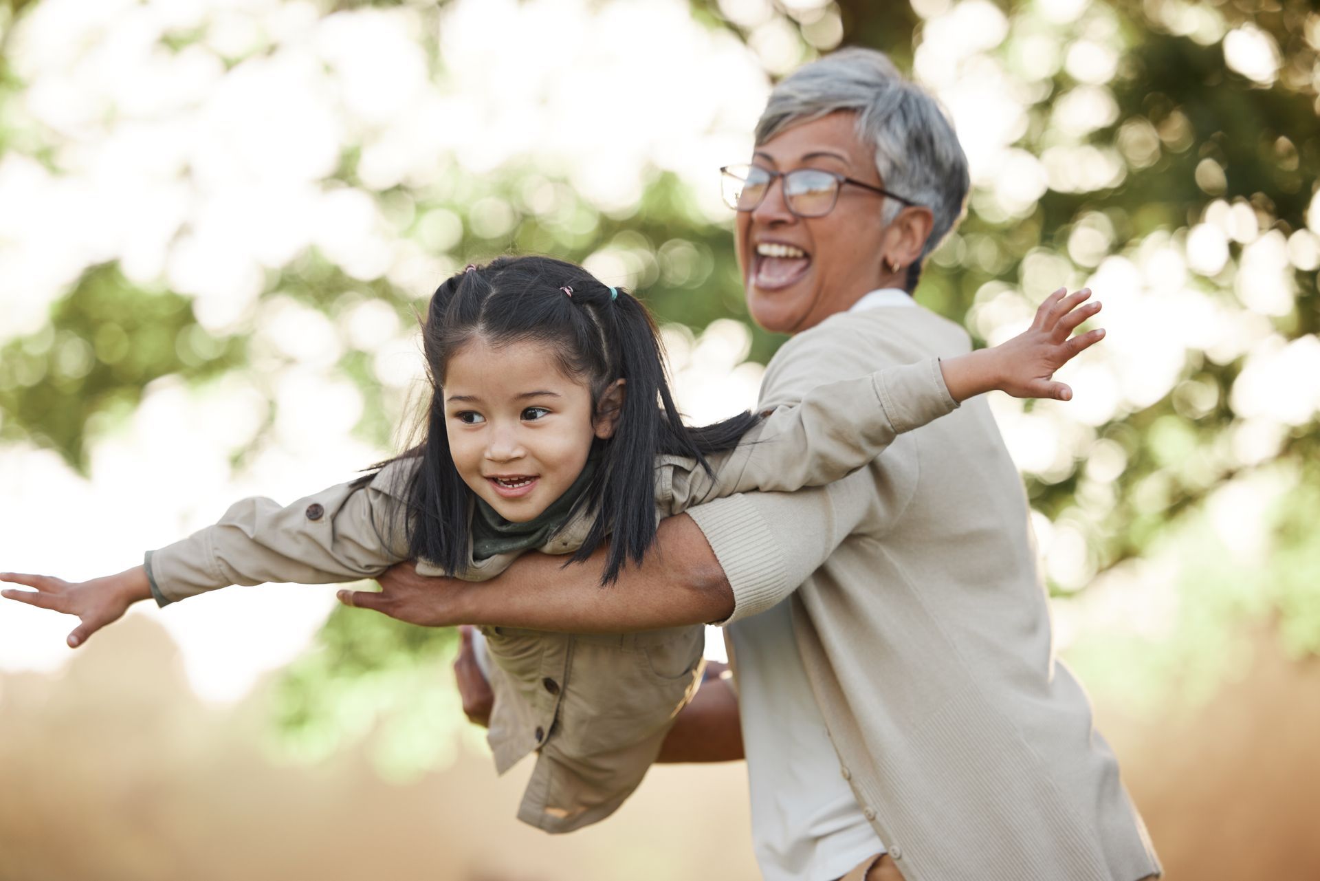 Grandmother swinging her granddaughter outdoors