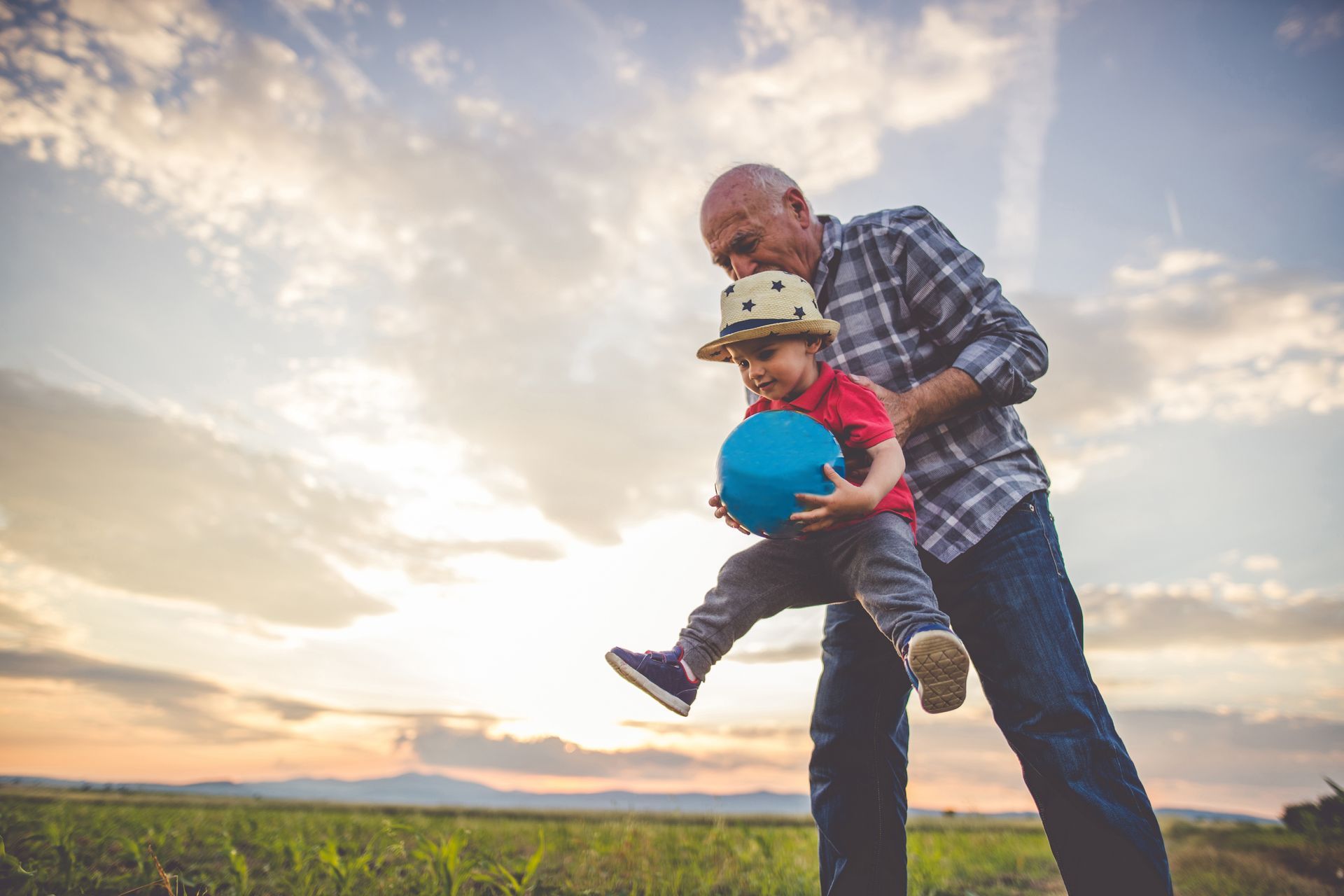 Grandfather playing ball with his grandson at sunset