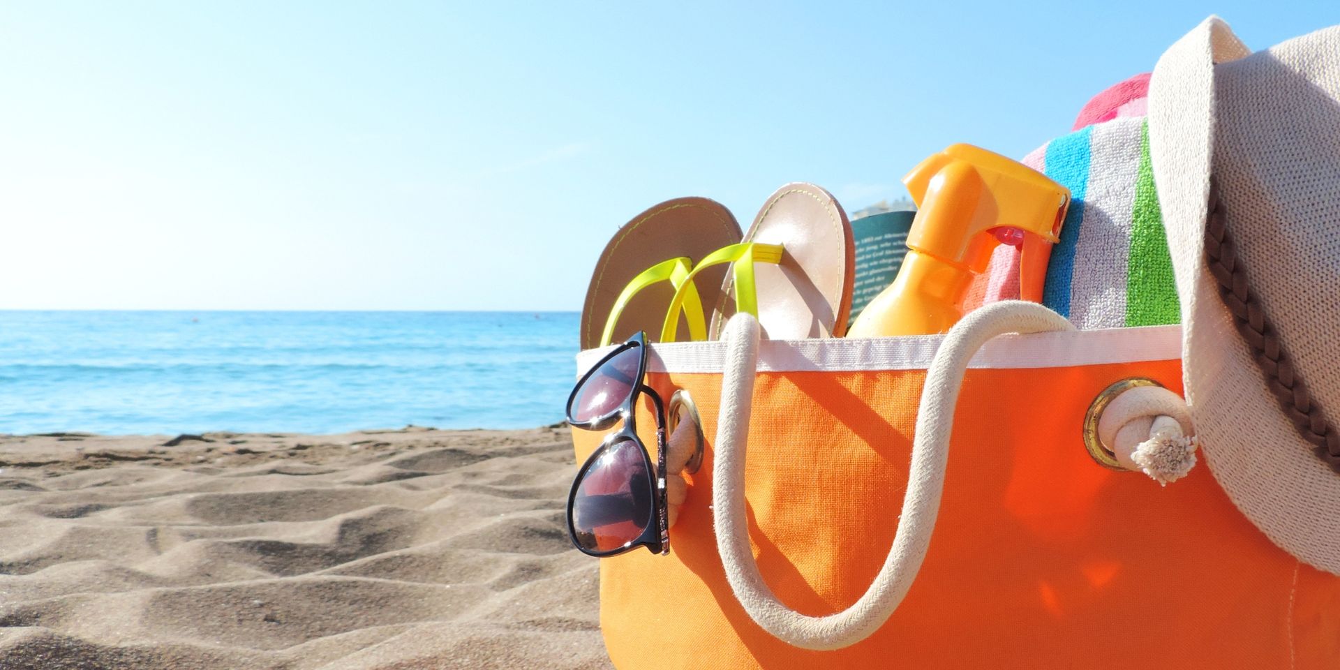 An orange beach bag on the sand at Carolina Beach, packed with vacation essentials