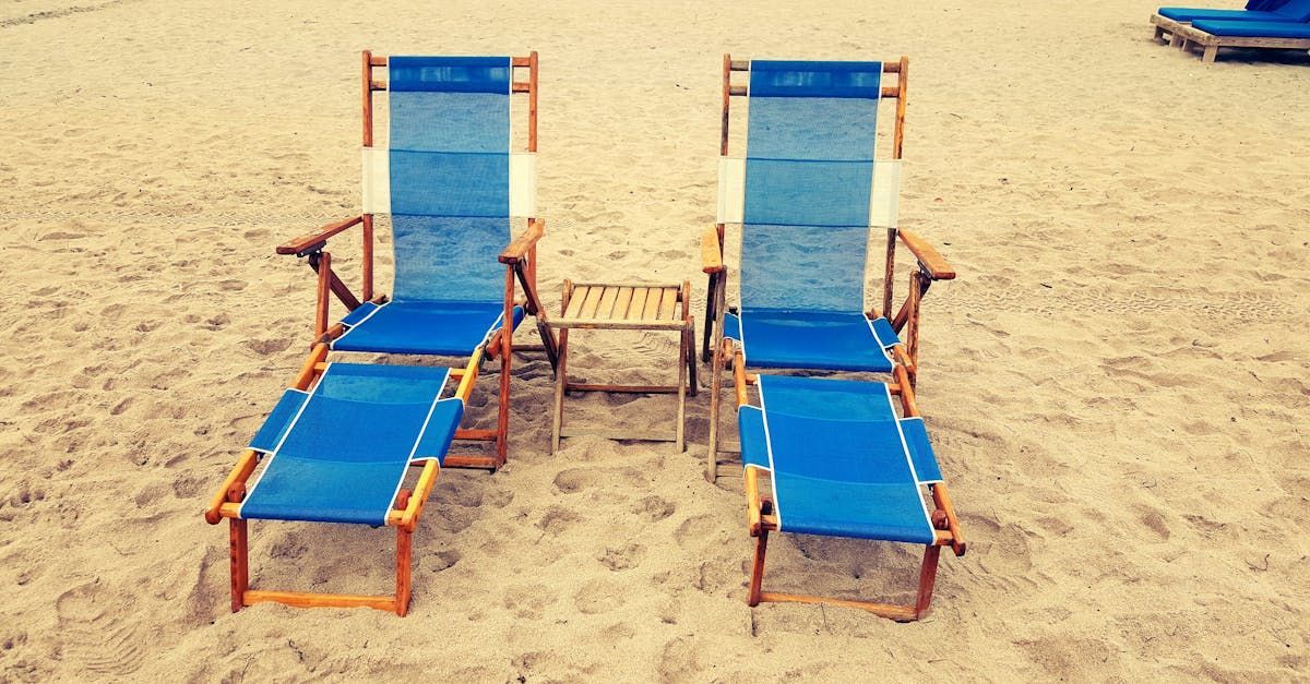 Two beach chairs and an umbrella set on a sunny beach, emphasizing the seaside relaxation available to guests at Seabirds Motel at Kure Beach, a perfect pet-friendly North Carolina lodging.