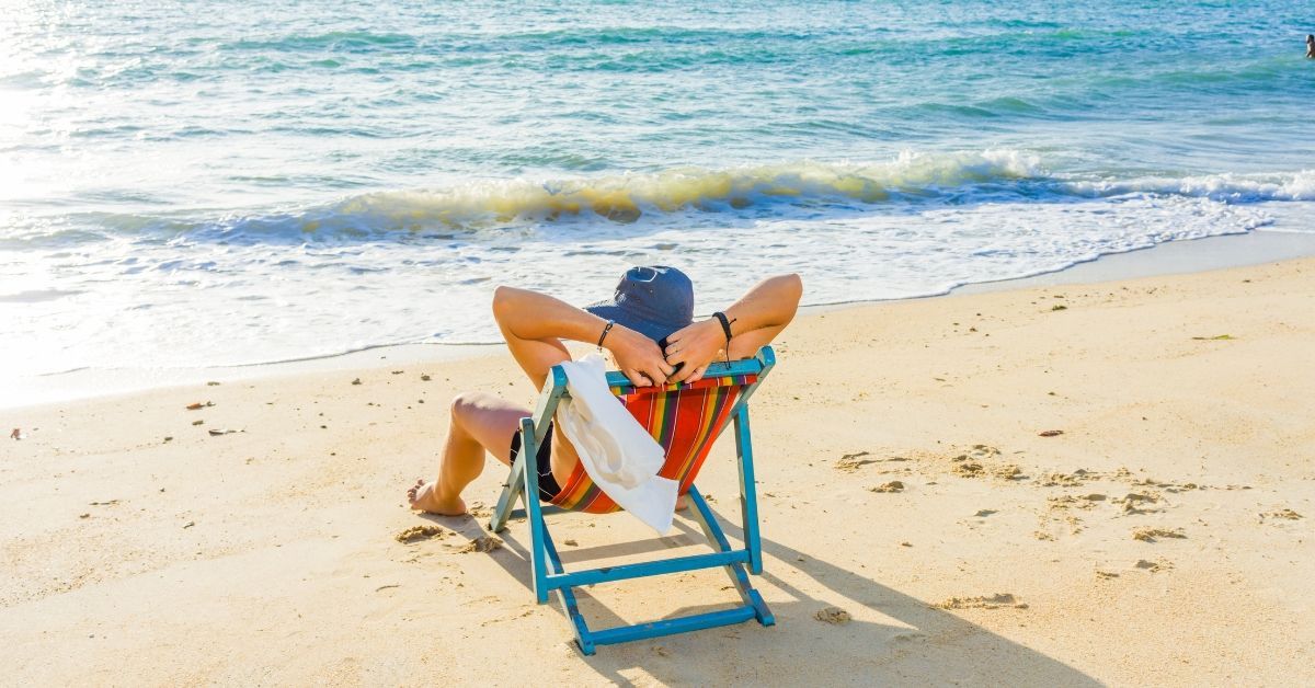 A person lounging on a colorful beach chair at Carolina Beach, enjoying the tranquil waves and sunny weather near Carolina Beach Motel.