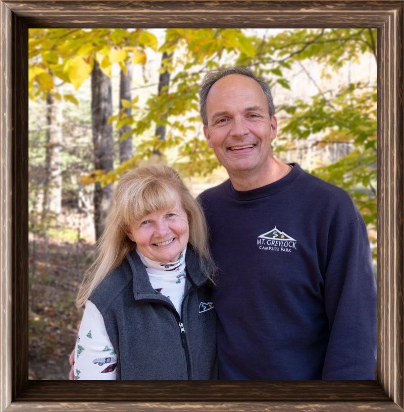 a man and a woman are posing for a picture in the woods .