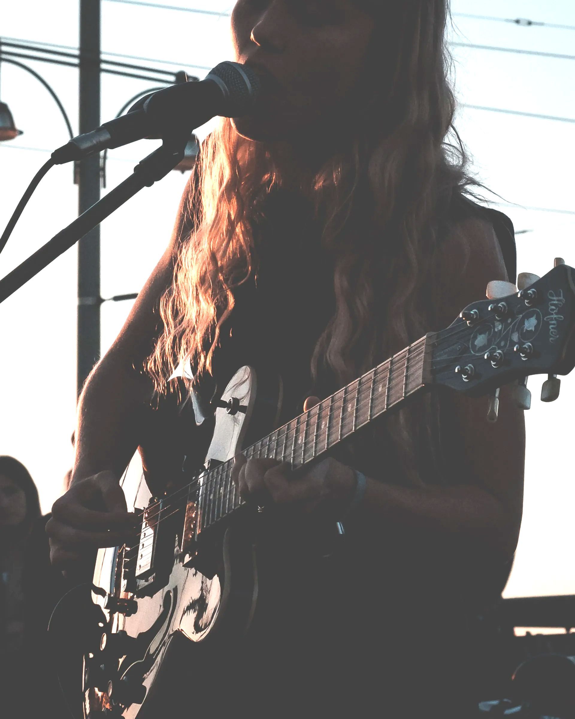 a woman singing into a microphone while playing a guitar