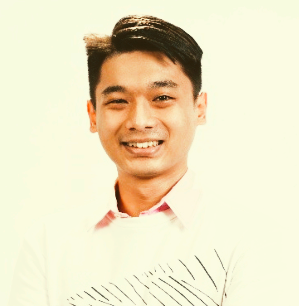 Smiling man in a white shirt against a light background, with a subtle leaf pattern at the bottom.