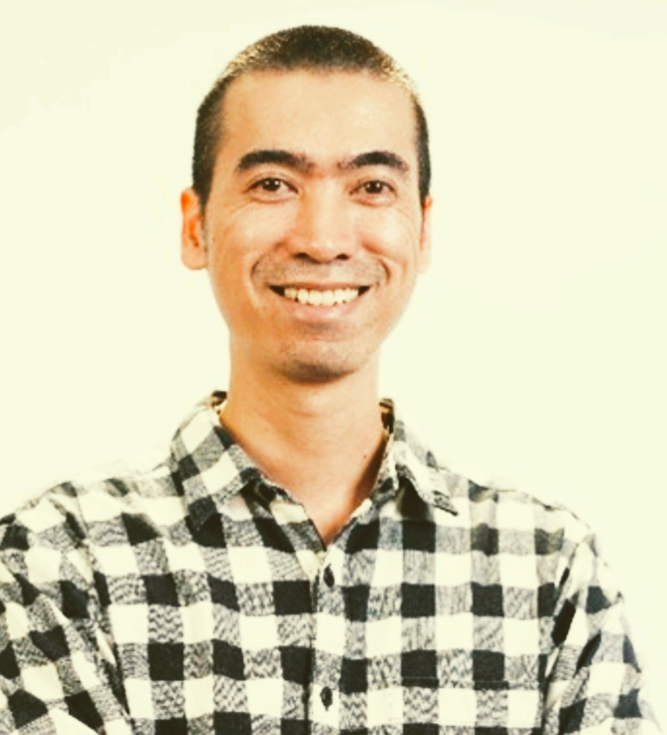 Smiling person in a black-and-white checkered shirt against a light background