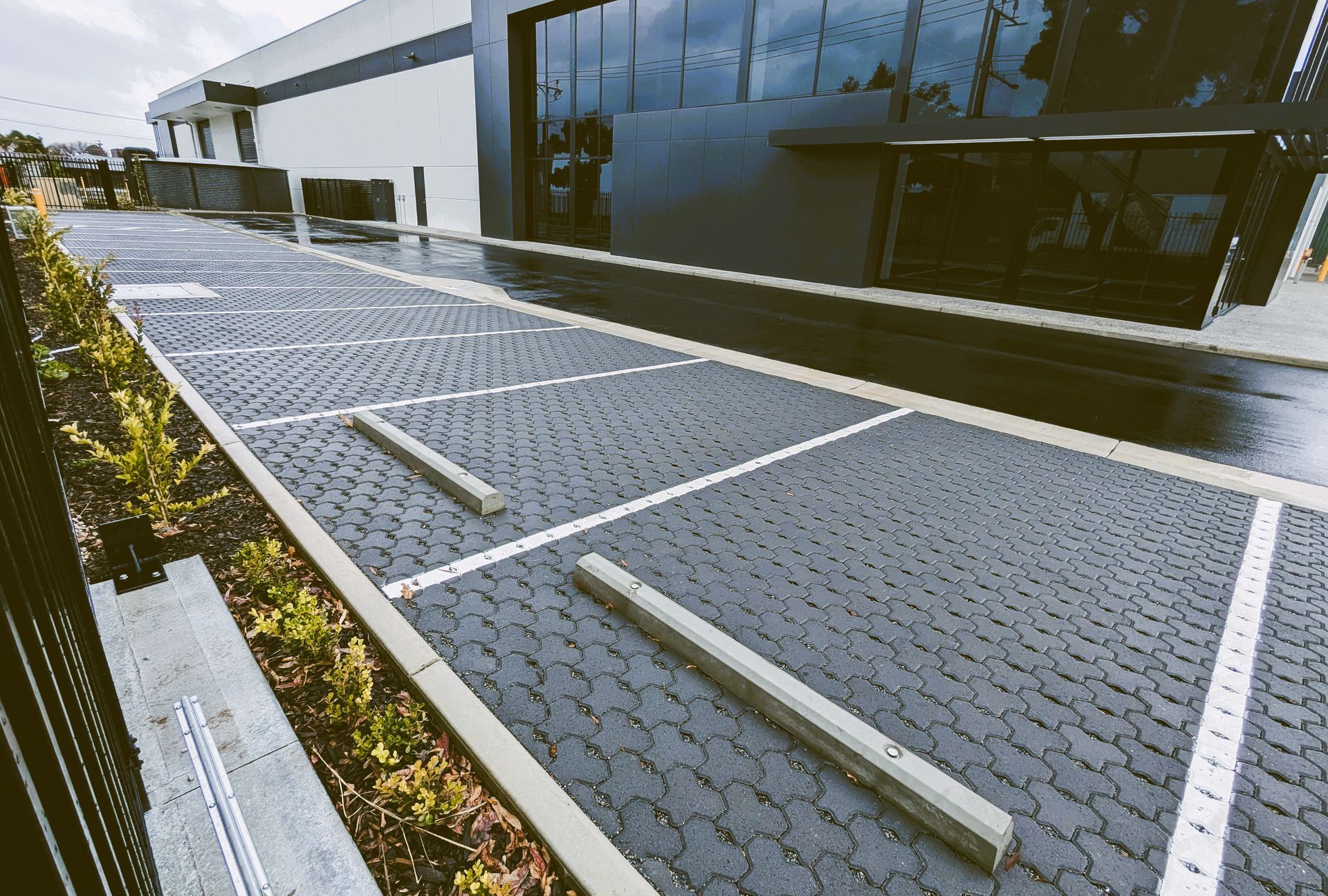Solar panel array mounted on a paved walkway beside a modern building