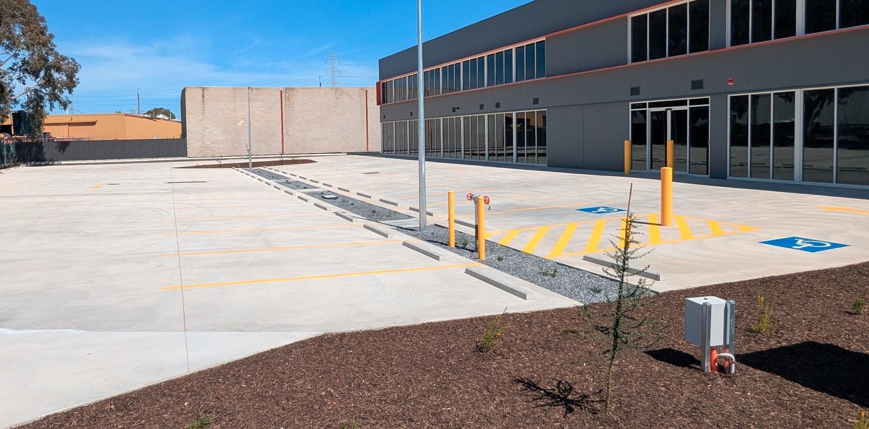 Exterior of a modern building with an accessible parking area, yellow curb ramps, and painted pavement markings