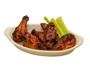 A white plate topped with chicken wings and celery sticks.