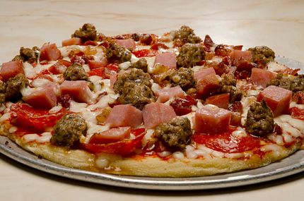 A pizza with ham and sausage on top of it