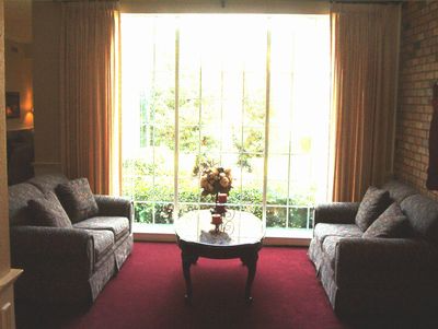 Living room with two gray sofas, a red rug, and a coffee table by a bright window