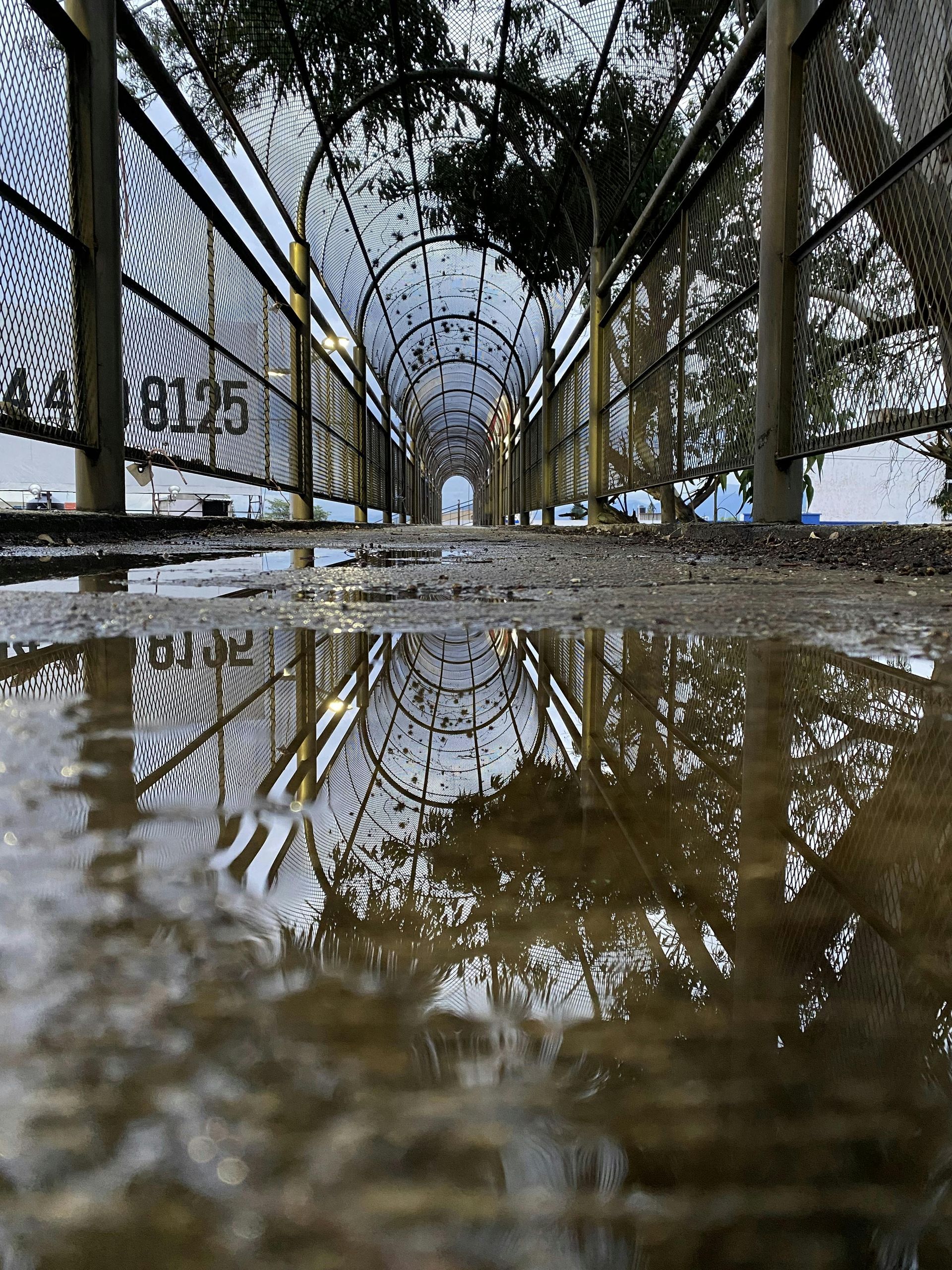 A bridge is reflected in a puddle of water.